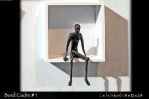 personnage en bronze assis sur le rebord d'une étagère